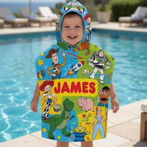 Puede incluir: Un ni&ntilde;o con una toalla con capucha azul, verde y amarilla con personajes de la pel&iacute;cula Toy Story. La toalla tiene el nombre "JAMES" impreso en letras rojas. El fondo muestra una piscina y tumbonas.