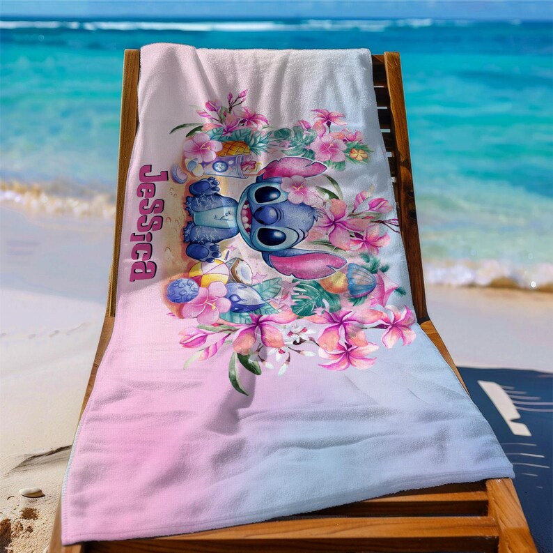 May include: A pink and blue beach towel with a cartoon Stitch character surrounded by tropical flowers. The towel has the name "Jessica" printed on it.