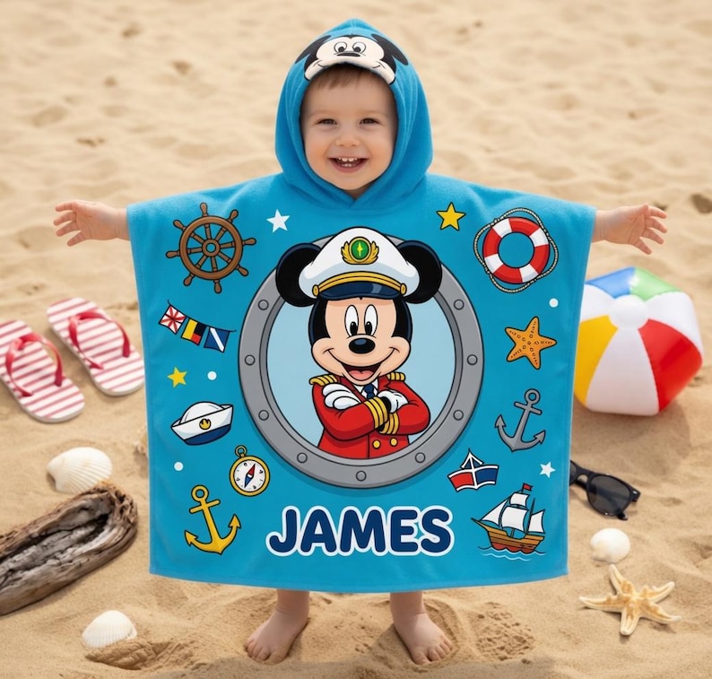 Op de afbeelding: Een lichtblauwe strandponcho met een Mickey Mouse kapitein ontwerp. De poncho is versierd met nautische symbolen zoals ankers, een scheepsstuur en een reddingsboei. De naam "JAMES" staat op de poncho. Perfect voor kinderen.