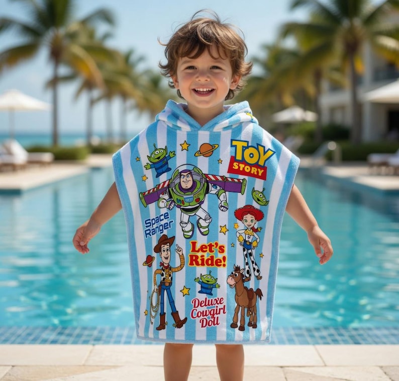 May include: A blue and white striped hooded towel featuring Toy Story characters. The towel has images of Buzz Lightyear, Woody, Jessie, and the Little Green Men. The words "Toy Story", "Space Ranger", "Let's Ride!", and "Deluxe Cowgirl Doll" are also printed on the towel.