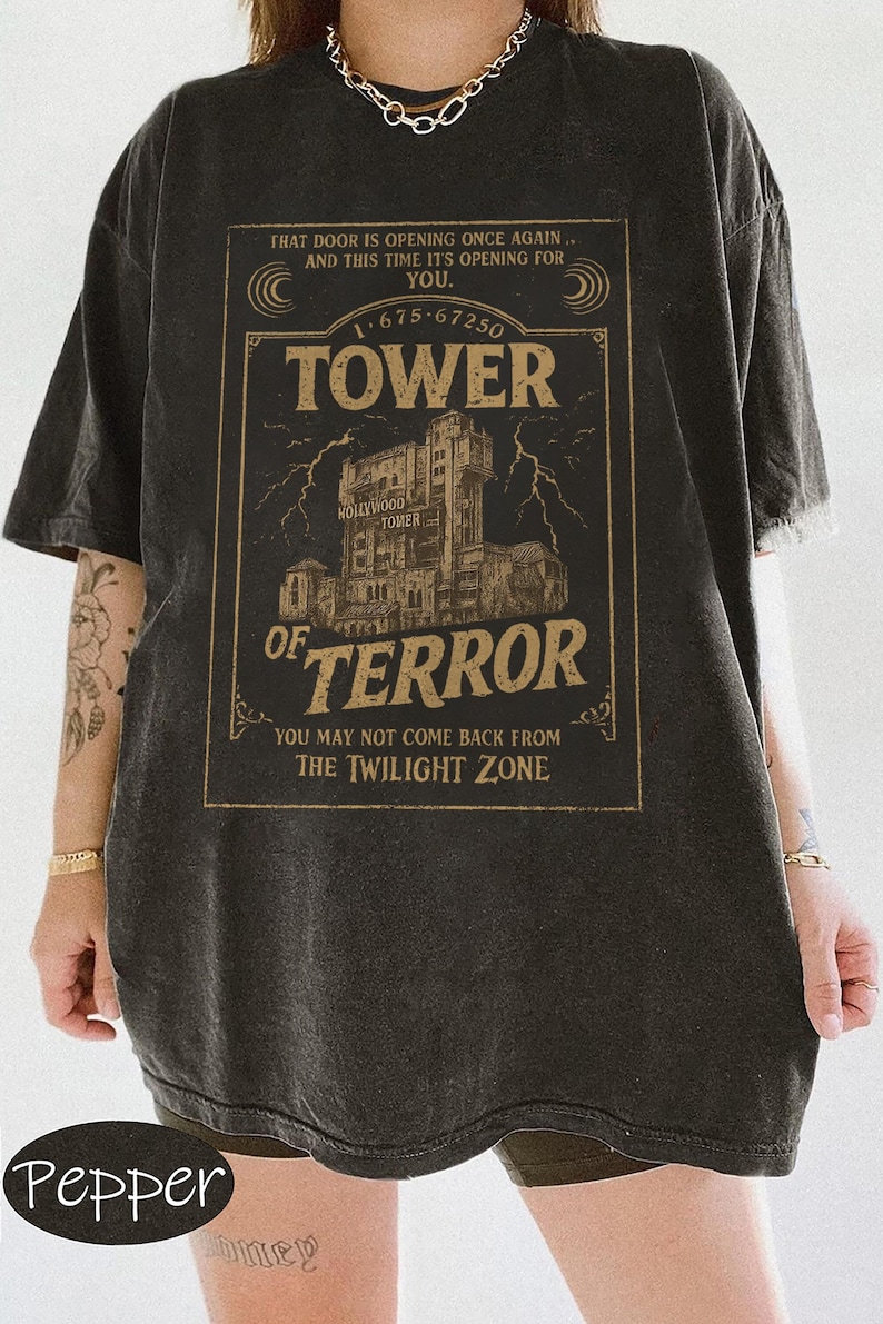 May include: Dark grey t-shirt with a vintage Tower of Terror graphic. The design includes the text "TOWER OF TERROR" with the Hollywood Tower Hotel illustration, lightning bolts, and the phrase "YOU MAY NOT COME BACK FROM THE TWILIGHT ZONE."