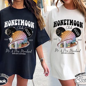 May include: Black and ivory t-shirts with a graphic design featuring the text "HONEYMOON Club 2025" and "Mr. & Mrs. Moreland EPCOT CENTER". The design includes a colorful sphere and fireworks.