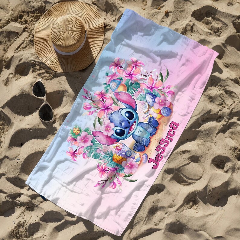 May include: A pink and blue beach towel with a cartoon Stitch character holding a tropical drink. The towel has a floral design and the name "Jessica" is written on it.