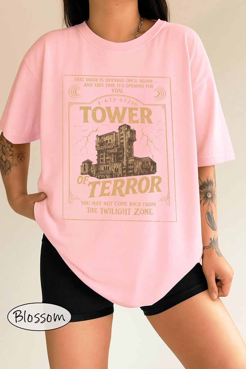 May include: Pale pink t-shirt with a gold-coloured graphic of the Hollywood Tower of Terror. The text on the shirt reads "Tower of Terror" and "You may not come back from the Twilight Zone." The shirt also has the text "That door is opening once again... and this time it's opening for you."