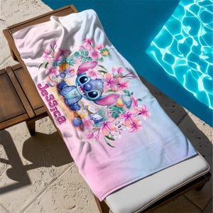 May include: A pink and blue beach towel with a cartoon Stitch character holding a tropical drink. The towel has a floral design with pink and white flowers. The text "Jessica" is printed on the towel.