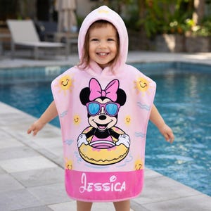 May include: Pink hooded beach towel featuring Minnie Mouse wearing sunglasses and a pink bow. The towel has a yellow inner tube, sun graphics, and the name "Jessica" in pink script.