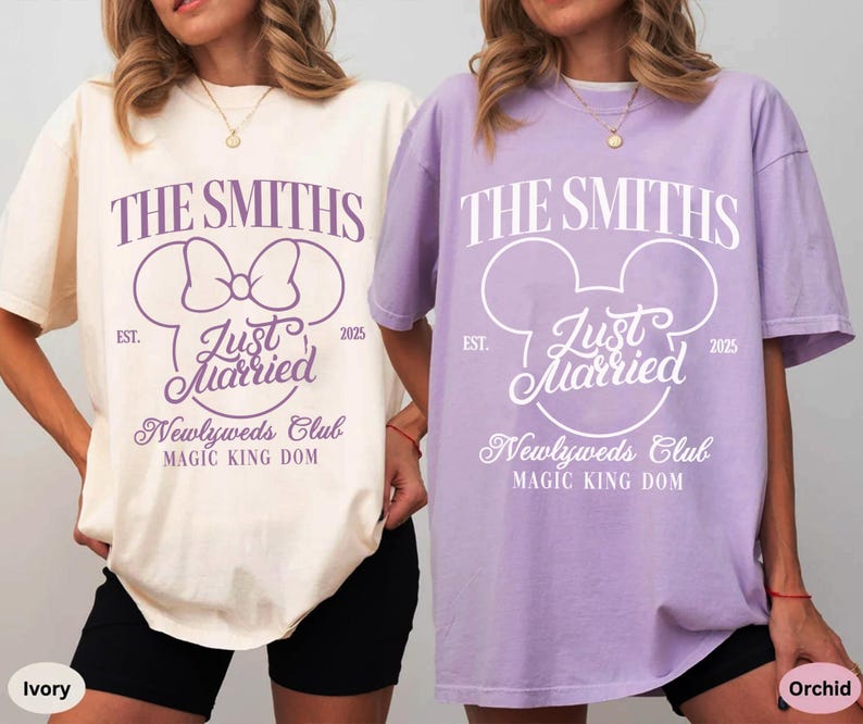 May include: Two oversized t-shirts, one ivory and one orchid, featuring a wedding-themed design. The design includes the text "THE SMITHS", "Just Married", and "Newlyweds Club", with a Mickey Mouse head silhouette. The shirts are for the "Magic King Dom" and the year "2025".