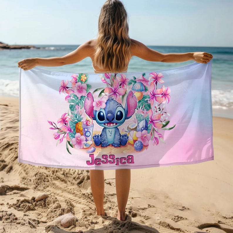 May include: A pink and blue beach towel with a cartoon Stitch character, tropical flowers, and the name "Jessica" printed on it.