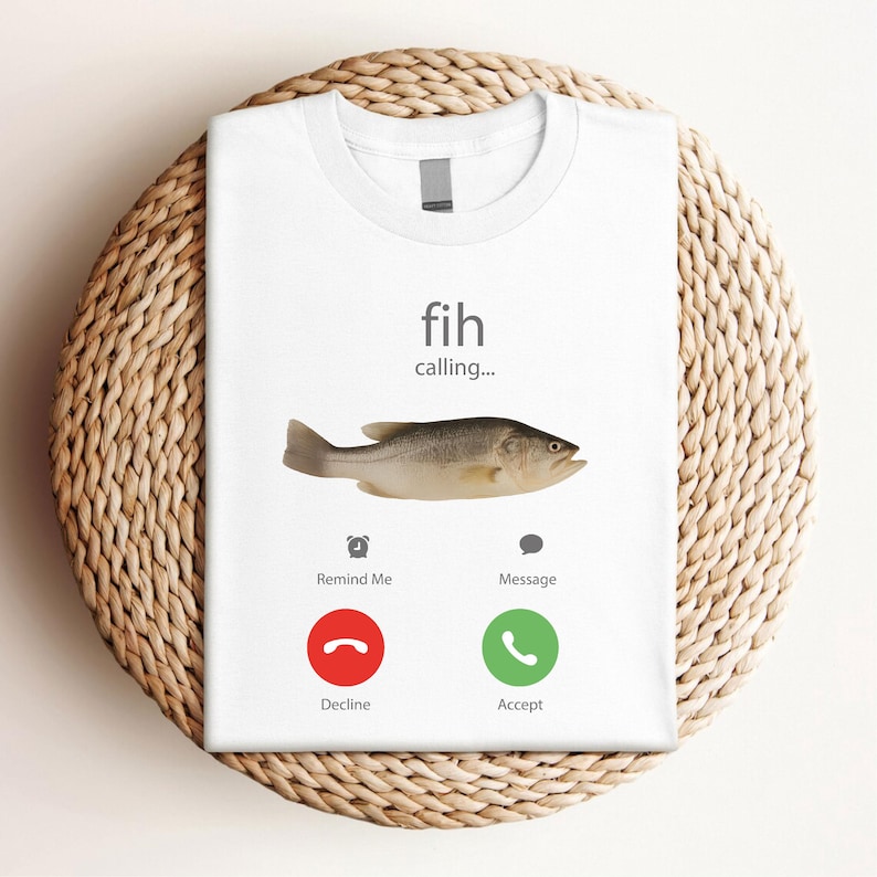 May include: White t-shirt with a humorous graphic of a fish, featuring the text "fih calling..." and a fish illustration. Below are icons for "Remind Me" and "Message", with "Decline" and "Accept" call buttons.