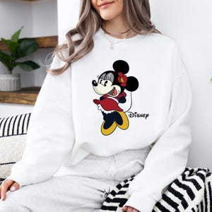 May include: White sweatshirt with a cartoon image of Minnie Mouse wearing a red dress and yellow shoes. The text "DISNEY" is printed below the image.
