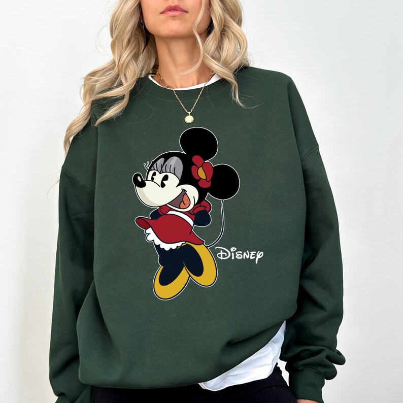 May include: A dark green sweatshirt with a cartoon image of Minnie Mouse wearing a red dress and a yellow bow. The text "DISNEY" is printed below the image.