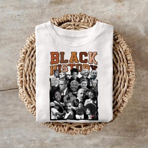 May include: White t-shirt with a collage of black and white photos of famous African Americans. The text "BLACK HISTORY" is printed in brown letters on the shirt.