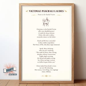 May include: Framed print with the text "VICTIMAE PASCHALI LAUDES" and "Praise to the Paschal Victim." The print features a lamb carrying a flag and religious text. The frame is a light brown color.