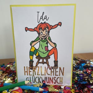 Puede incluir: Una tarjeta de felicitaci&oacute;n con una ilustraci&oacute;n de dibujos animados de una ni&ntilde;a con cabello rojo y un vestido verde. La tarjeta dice "Ida" y "Herzlichen Gl&uuml;ckwunsch", que se traduce como "Felicidades".