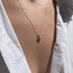 May include: A silver chain necklace with a small silver cross pendant.