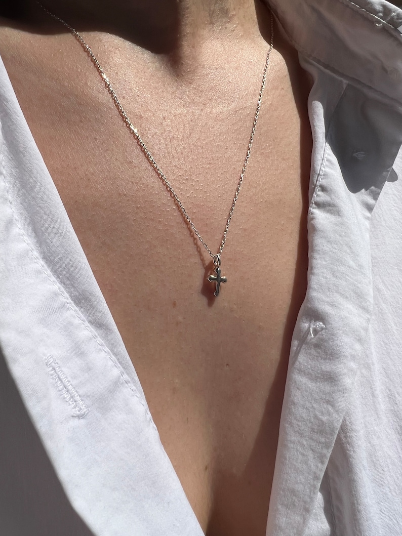 May include: A silver chain necklace with a small silver cross pendant.