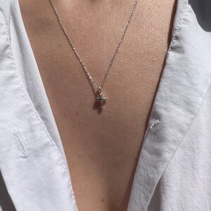 May include: A silver chain necklace with a small silver cross pendant.
