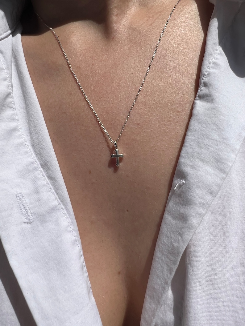 May include: A silver chain necklace with a small silver cross pendant.
