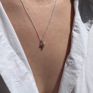 May include: A silver chain necklace with a small silver cross pendant.