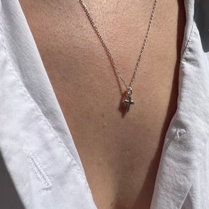 May include: A silver chain necklace with a small silver cross pendant.