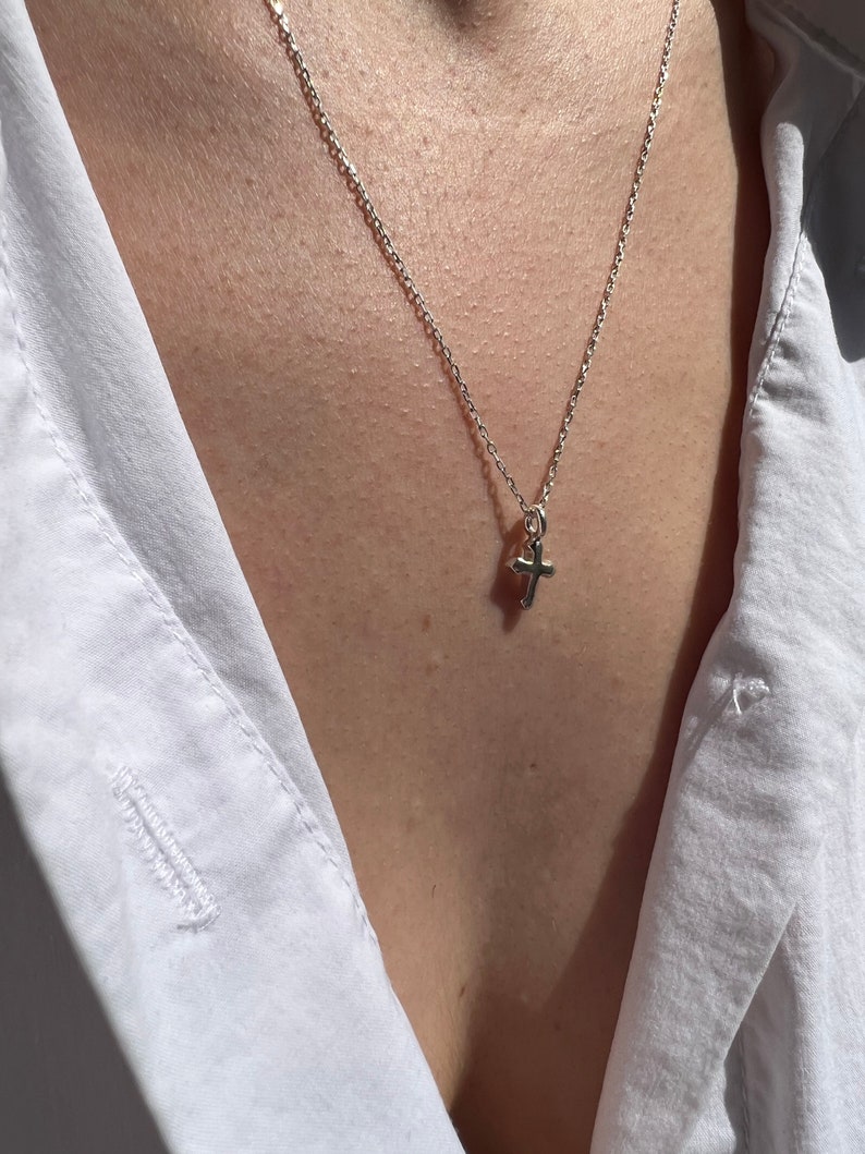 May include: A silver chain necklace with a small silver cross pendant.