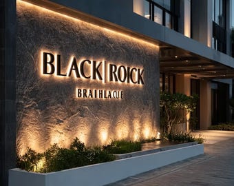 May include: An exterior shot of a building with a stone facade. The illuminated sign reads "BLACK ROICK BRAITHLAQUE" in a sans-serif font. The sign is lit from behind, creating a warm glow. Green plants are in a white planter below.