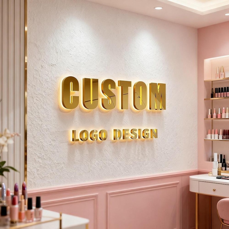 May include: A wall-mounted sign featuring the word CUSTOM in large, reflective gold 3D lettering above the words LOGO DESIGN in smaller gold 3D lettering. The letters are illuminated from behind, casting a soft glow against the textured white wall.