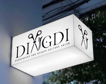 Op de afbeelding: Een wit rechthoekig bord met zwarte tekst en een schaarlogo. Het bord luidt "DIVGDI Barbershop and Beauty Culture Salon".