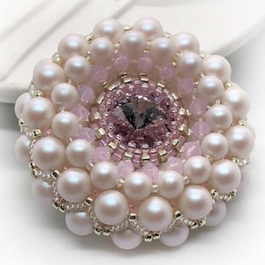 May include: A pink and white beaded brooch with a large, faceted, purple crystal in the center.