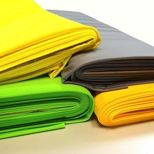 May include: Four rolls of fabric in different colors: yellow, green, gray, and a lighter yellow. The fabric is folded and stacked on top of each other.