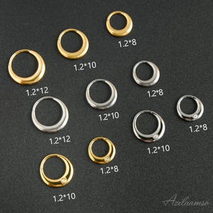 Może przedstawiać: Zestaw złotych i srebrnych kolczyków w kształcie kółek, niektóre z małym kamieniem, na ciemnym tle. Rozmiary, takie jak 1.2*8, 1.2*10 i 1.2*12, są podane w milimetrach.
