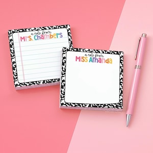 May include: Two square sticky note pads with a black and white cow print border. One pad features horizontal lines and the text A note from Mrs. Chambers. The other pad is blank with the text A note from Miss Amanda. A light pink ballpoint pen is included.