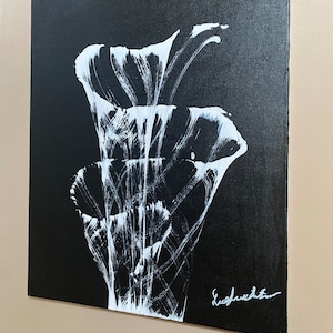 Pu&ograve; includere: Dipinto astratto in bianco e nero di un fiore stilizzato con una firma bianca in basso a destra.