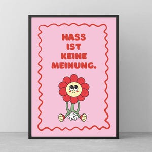 Peut inclure: Une affiche encadrée avec un fond rose et une bordure rouge ondulée. L'affiche présente une fleur de dessin animé avec un visage souriant et le texte allemand "Hass ist keine Meinung" en lettres rouges.
