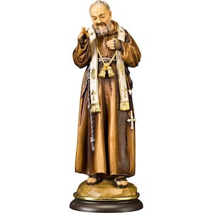 Könnte beinhalten: Eine Holzstatue des Heiligen Padre Pio, eines katholischen Priesters, der eine braune Robe und eine weiße Stola trägt. Er hält einen Rosenkranz in seiner rechten Hand und hat ein Kreuz auf seiner Brust.