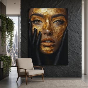 Puede incluir: Una gran impresión de arte mural rectangular que presenta un retrato en primer plano de un rostro parcialmente cubierto con pan de oro texturizado. El sujeto tiene piel oscura, ojos marrones y manos pintadas de negro que enmarcan el rostro.