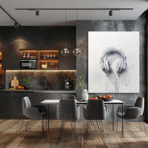 May include: A modern dining room with a dark grey kitchen and a dining table with four grey chairs. A large white canvas painting with a watercolor illustration of a pair of headphones hangs on the wall.