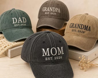 Könnte beinhalten: Vier Baseballkappen in Grün-, Braun- und Schwarztönen. Jede Kappe ist mit einem Titel bestickt: "DAD", "GRANDPA", "GRANDMA" und "MOM", gefolgt von "EST. 2026". Die Kappen sind auf einem neutralen Hintergrund angeordnet.