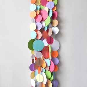 May include: A colorful paper circle garland with a variety of colors including pink, green, blue, orange, yellow, and purple.