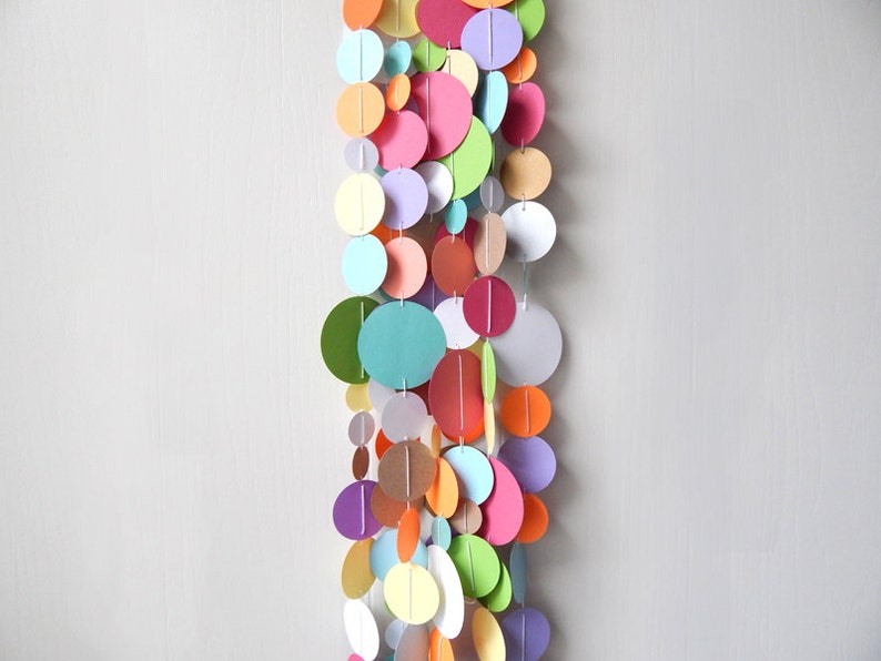 May include: A colorful paper circle garland with a variety of colors including pink, green, blue, orange, yellow, and purple.