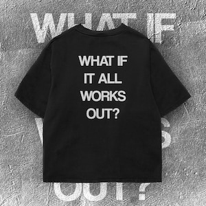 May include: A black short-sleeved t-shirt featuring the white text "WHAT IF IT ALL WORKS OUT?" printed in a bold, sans-serif font on the centre of the chest. The garment has a classic crew neckline and a straight hemline, presenting a clean design.