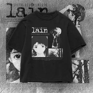 May include: A black short-sleeve t-shirt featuring a white graphic print from Serial Experiments Lain. The design includes the text 'serial experiments lain', a portrait of a character, a figure standing, and a small scene of power lines.