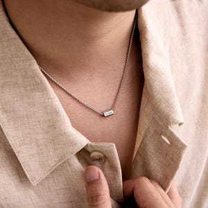 May include: A silver chain necklace with a small rectangular pendant that says "Andrew" on it.