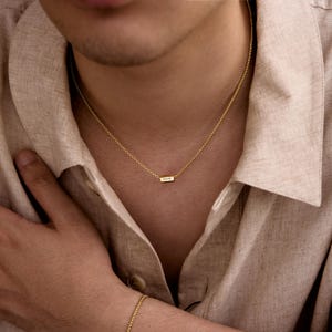 May include: A gold chain necklace with a small rectangular pendant that says "LOVE" on it.