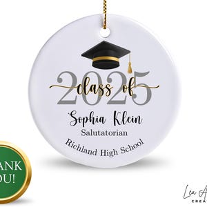 May include: White graduation ornament with a black mortarboard, gold tassel, and the text "Class of 2025." Includes the name "Sophia Klein," "Salutatorian," and "Richland High School." A gold cord is attached for hanging.