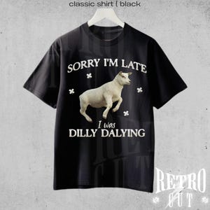 May include: Black t-shirt with white text that reads "Sorry I'm Late I was Dilly Dallying" and a white sheep illustration.