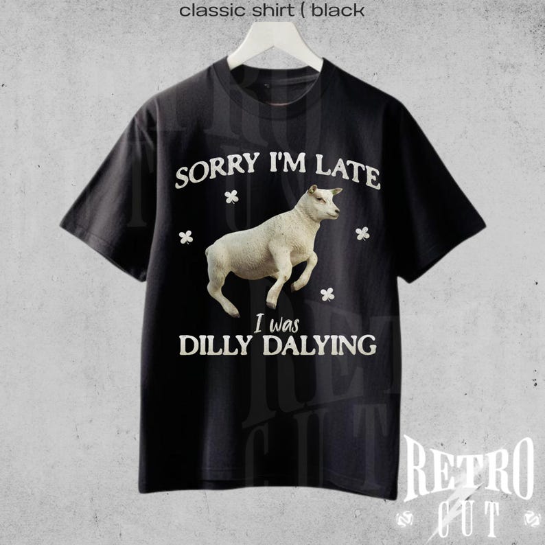 May include: Black t-shirt with white text that reads "Sorry I'm Late I was Dilly Dallying" and a white sheep illustration.