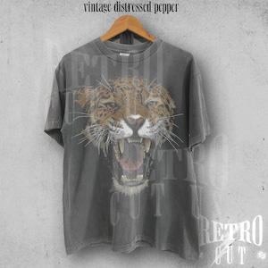 May include: A grey vintage t-shirt with a distressed look featuring a graphic of a snarling jaguar with a black and brown spotted pattern.