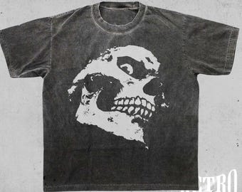 May include: A black t-shirt with a vintage washed look features a white skull graphic with a third eye. The text "vintage washed (pepper)" is printed at the top of the shirt.