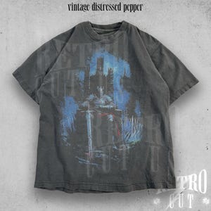 May include: A vintage black t-shirt with a distressed look featuring a graphic print of a knight in armor sitting on a throne with a sword in hand. The background is a dark blue and purple castle scene.